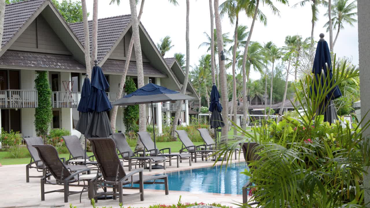 Statisk vidvinkelbillede af et luksuriøst tropisk resort med villaer, swimmingpool og palmer.