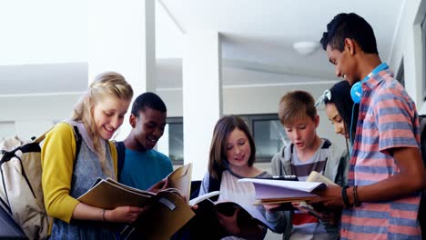 Gruppe-Lächelnder-Studenten,-Die-Mit-Einem-Notizbuch-Im-Flur-Stehen