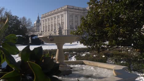 birds dance on frozen fountain in front of the royal palace of madrid