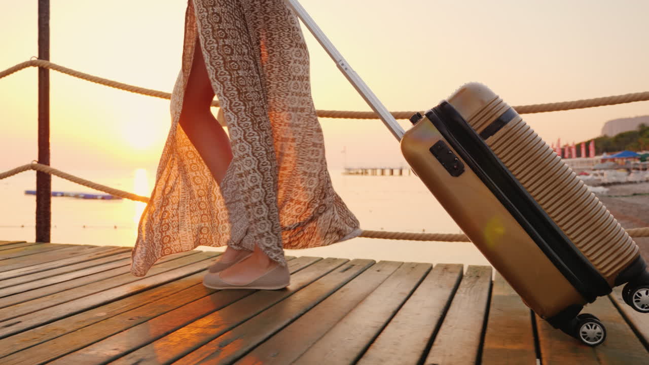 uma mulher com uma bolsa sobre rodas cavalga o píer em direção ao mar o sol nascente ilumina lindamente h
