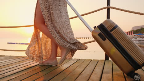 a woman with a bag on wheels rides the pier towards the sea the rising sun beautifully illuminates h