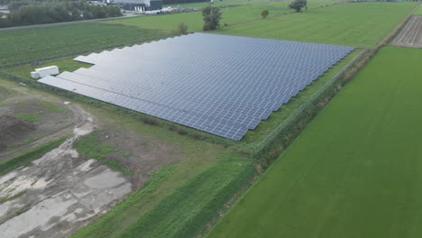 Wide-aerial-of-large-solar-panel-park-surrounded-by-green-meadows