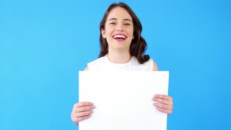 hermosa mujer sosteniendo un cartel en blanco sobre un fondo azul