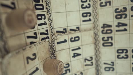un video macro vertical de un tablero de bingo, luces de estudio, 120 fps, cámara lenta, dígitos de chips de madera, imágenes en bruto, juego de mesa de lotería vintage, números de cartas, empuje de grúa en movimiento suave