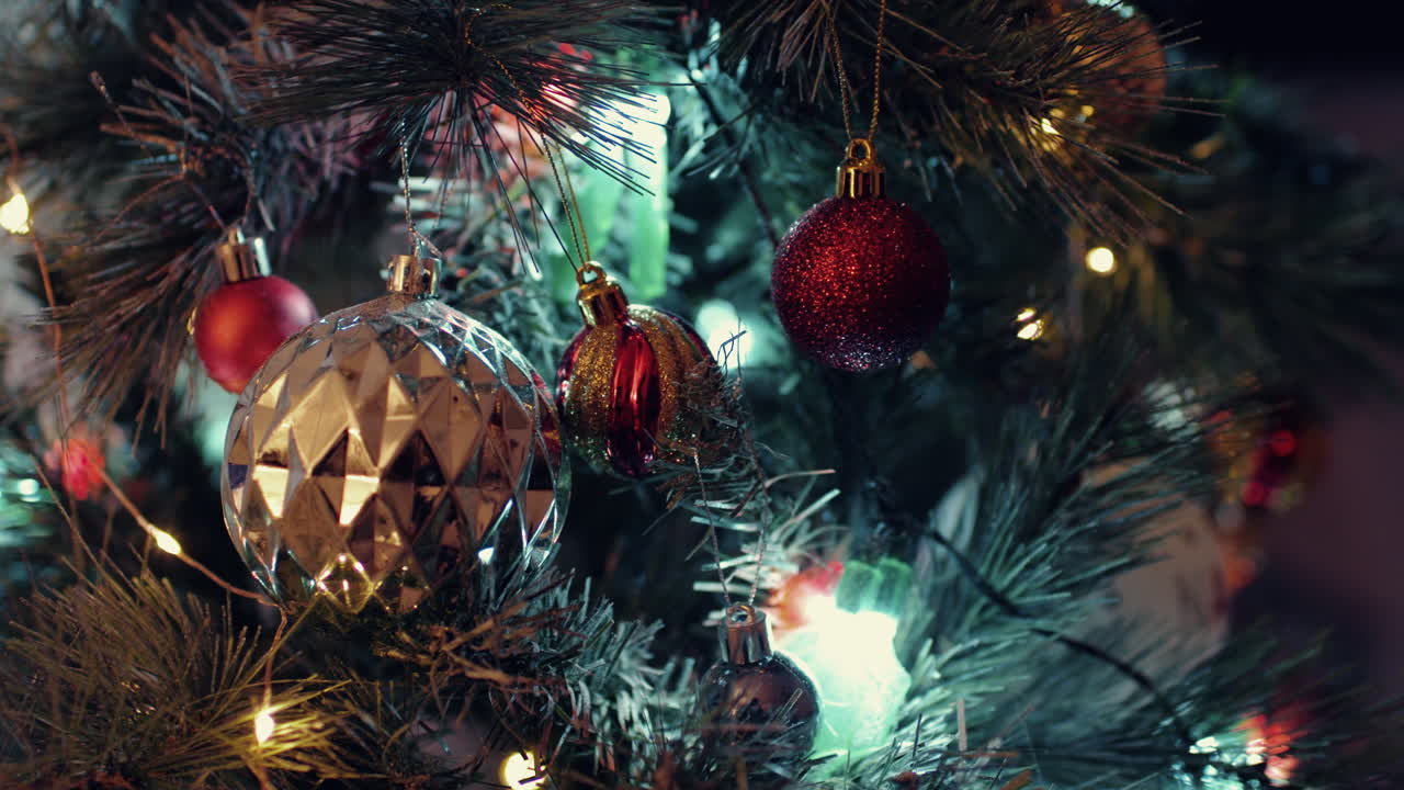 atractivos adornos de bolas de oro y rojo brillante colgados en el árbol de navidad - primer plano, tiro deslizante