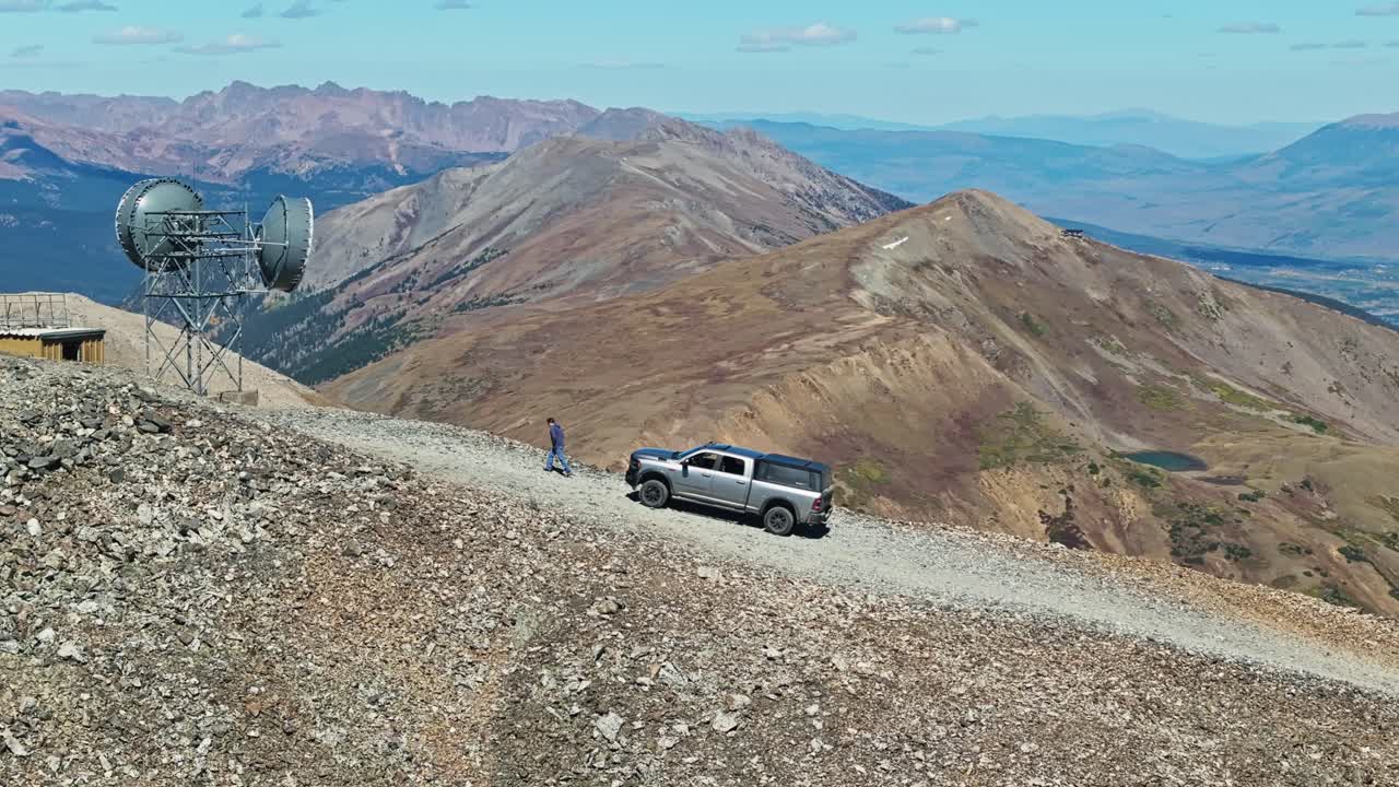 Aerial telephoto parallax above truck as driver walks out from Peak 10 trail summit in Breckenridge Colorado