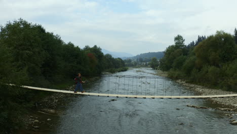 Lovers-crossing-forest-river-going-camp-trekking-activity-mountains-background