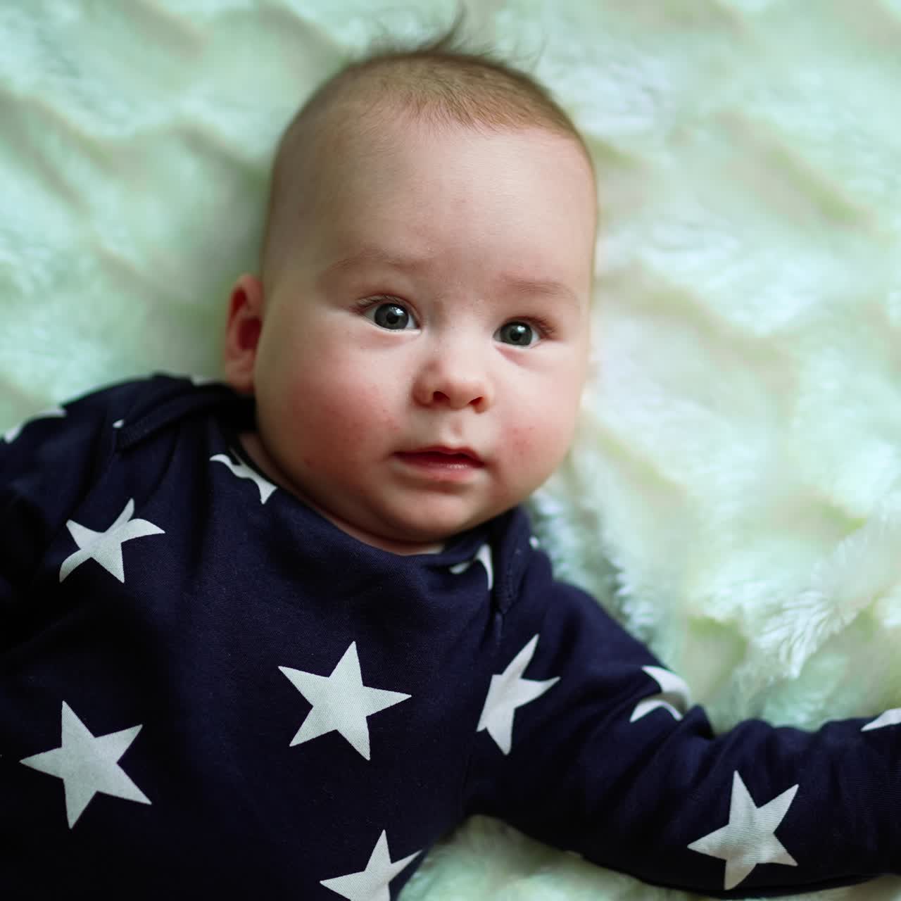 Playful baby laying on the bed. Adorable happy little kid smilling
