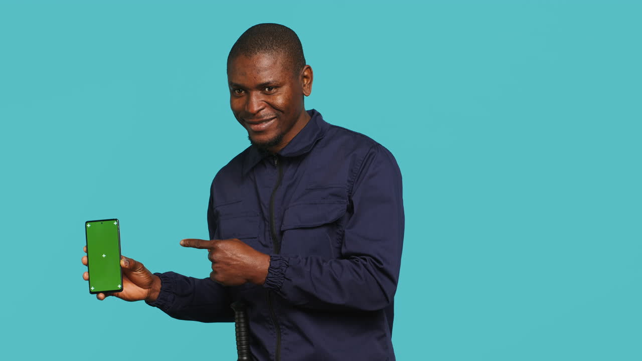 Portrait of upbeat bodyguard showcasing green screen phone