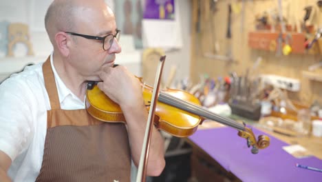 maestro luthier tocando el violín en el taller