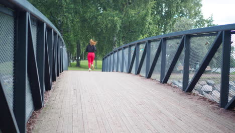 Young-girl-running-across-a-bridge-in-a-park