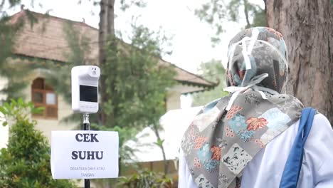 yogyakarta, indonesia - mar 8, 2021 : visitors are checking body temperature using a portable thermo gun