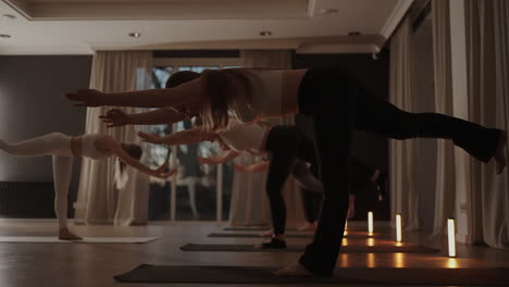 A-group-of-women-is-engaged-in-stretching-and-balance-with-an-instructor-in-a-beautiful-hall-with-large-windows.-Healthy-lifestyle-group-classes