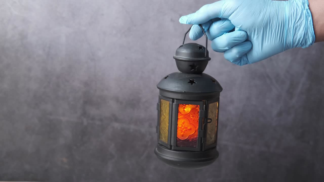 검은색 배경에 랜턴 불빛을 들고 손바닥에 장갑을 고 있습니다.