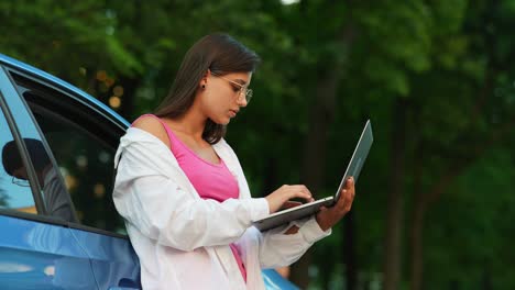 mujer joven trabajando en una computadora portátil junto a un coche