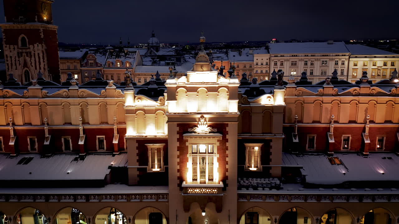 Aerial view of snow covered Sukiennice (Cloth Hall) on Main Market Square with Christmas stalls at night in Krakow, Poland