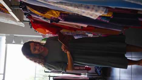 video vertical de una mujer propietaria o trabajadora en una tienda de ropa de moda comprobando el stock con una tableta digital