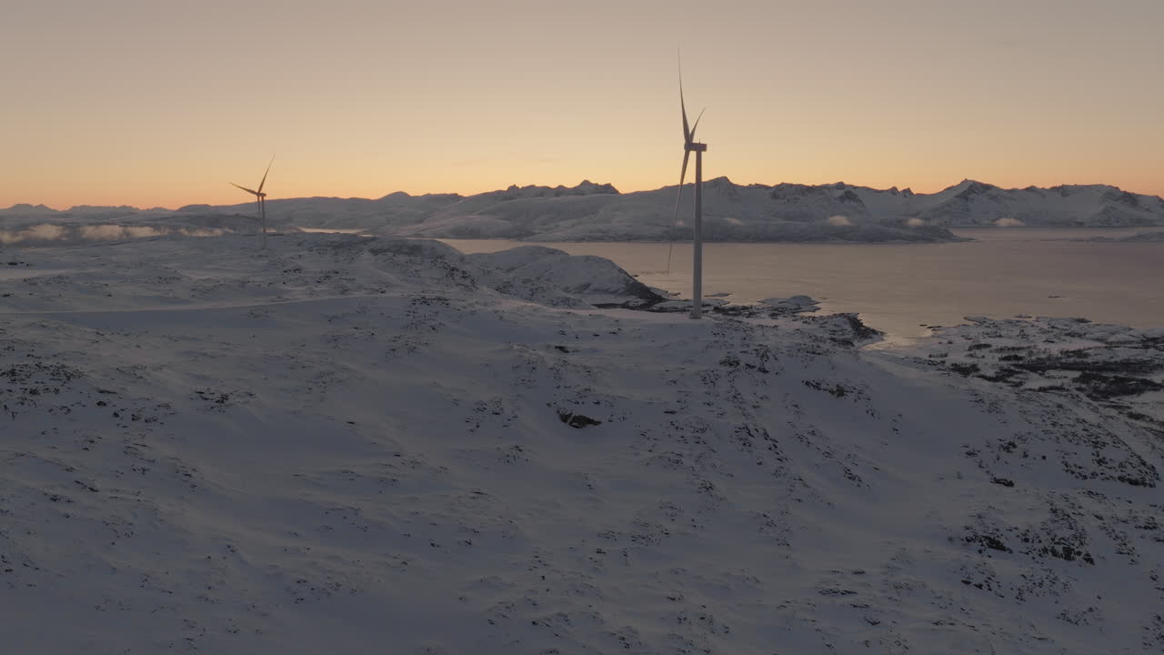 일몰 시 북극 겨울 풍경의 능선에 있는 풍력 터빈, 드론 슬로우 모션