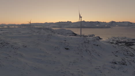 wind turbines on ridge in arctic winter landscape at sunset, drone slow motion