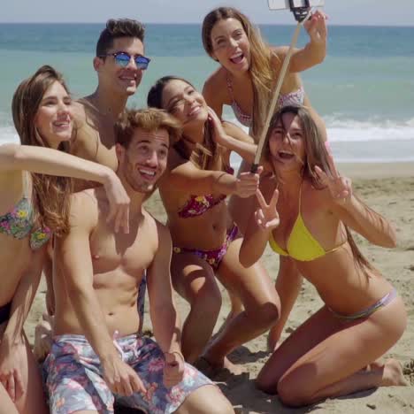 group of friends with metal detector on beach