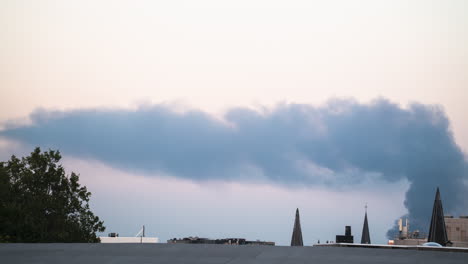 a column of smoke rises over the roofs in antwerp, belgium