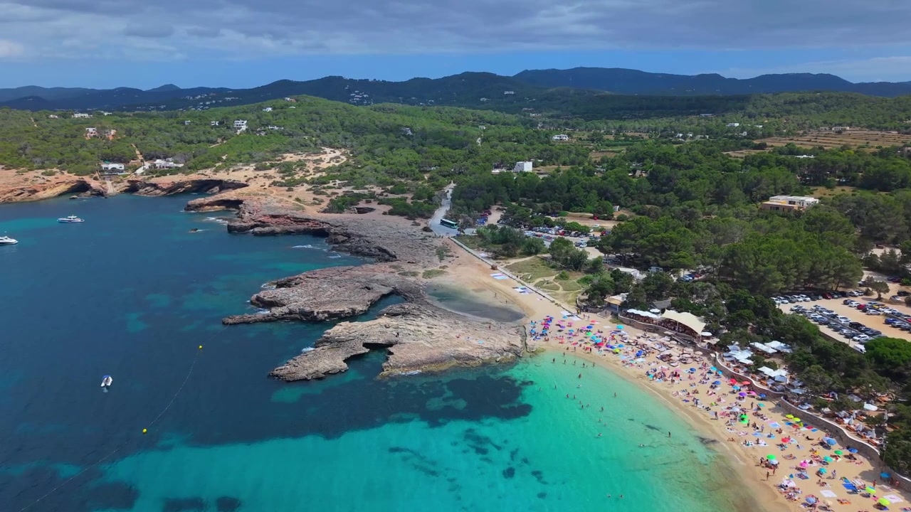 Ripresa dall'alto della baia di Cala Bassa circondata da coste rocciose e pini verdi