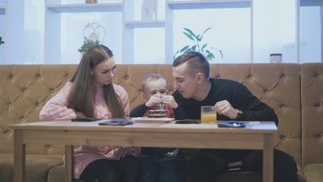 man-and-son-drink-water-with-plastic-straws-sitting-by-lady