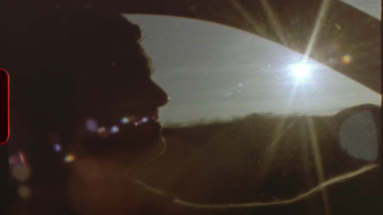 Filmed on super 8 film Light leaks and film grain - a man driving a car, with the sun shining through the windshield