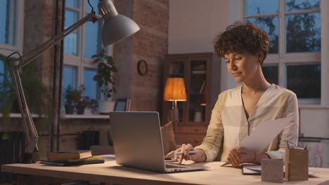 mujer con el pelo corto y rizado sentada en un escritorio frente a la computadora mientras presenta un proyecto