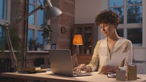 woman with short curly hair sitting at a desk in front of the computer while presenting a project