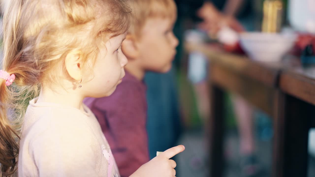 클로즈업 아이들이 벤치 위에 여름 집에 앉아 점심을 먹고 있습니다.