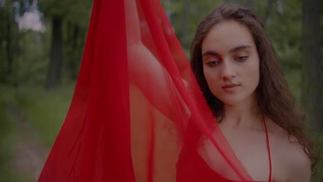 pensive woman in red dress in forest