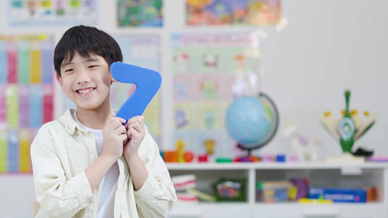 밝고 화려한 교실에서 파란색 폼 재질의 숫자 7을 들고 있는 행복한 초등학생