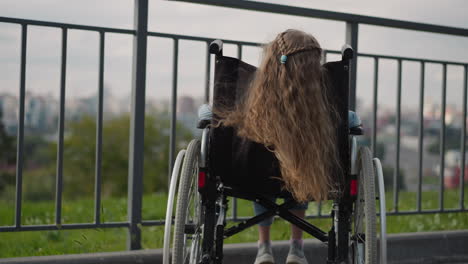 Long ginger hair of little girl in wheelchair waves in wind