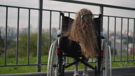 long ginger hair of little girl in wheelchair waves in wind