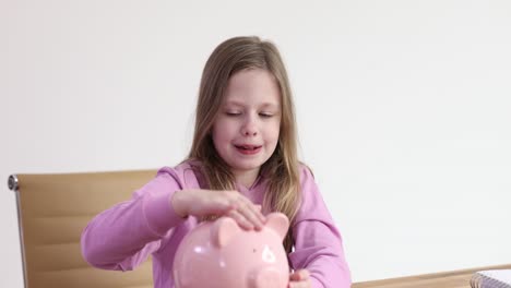 young girl saving money in a pink piggy bank