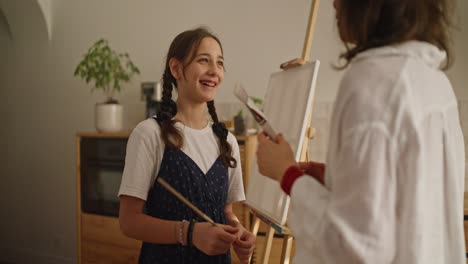 teenage girl painting with mother