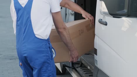 two young workers of removal company are loading boxes and furniture into a minibus