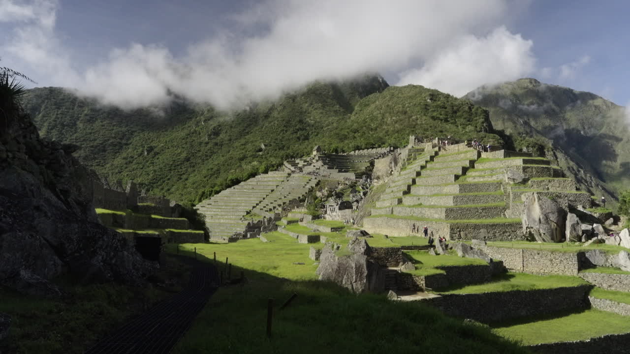 Wide panning view of Machu Picchu, Cusco Peru. Ancient Machu Pichu lost city landscape. Sunny