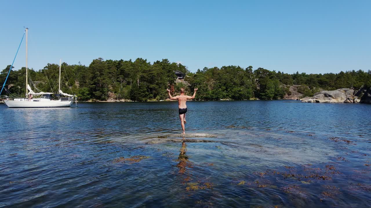Drone orbit shot man on shallow water Stockholm archipelago yacht summer view