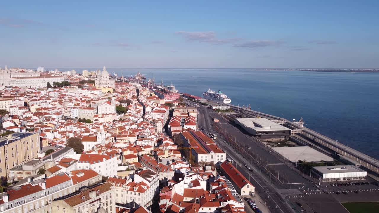 Drone making sideway movement on a bright sunny Lisbon Alfama Portugal day in Winter with large Cruise Ship in Harbour of the bay