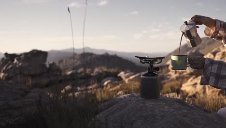 scenic view of coffee being poured into a cup on a mountain top while camping