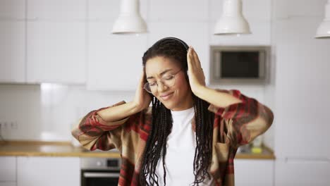 Porträt-Einer-Jungen-Afroamerikanischen-Frau,-Die-Kopfhörer-Trägt-Und-Zu-Hause-Musik-Hört