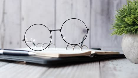 stylish office desk setup with glasses, notebook and pen