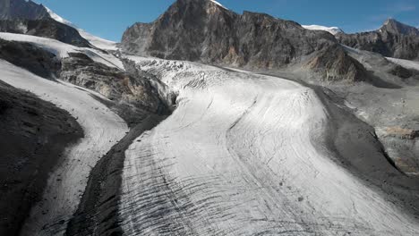 aerial flyover over the allalin glacier near saas-fee in valais, switzerland with a pan down view from the allalinhorn peak down to the ice and crevasses on a sunny summer day in the swiss alps