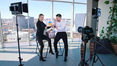 creative people discussing business ideas showing design project in office. young businessman and woman standing at desk and talking in front of professional cameras in light studio.