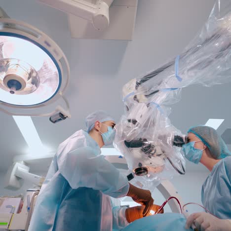 neurosurgeons in the operating theatre. surgeons perform surgery on patient through modern microscope at the hospital. view from below.