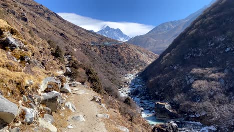 un valle en las montañas del himalaya con un río en el fondo y picos nevados en el fondo