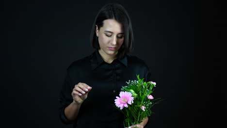 Young-Lonely-Woman-Tears-Off-Leaves-of-Purple-Flower,-Slow-Motion,-Black-Background