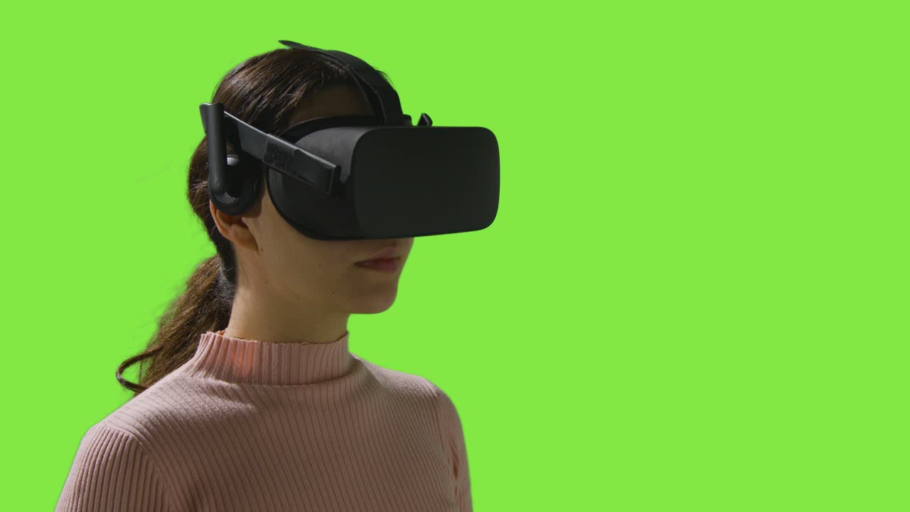 Woman Putting On Virtual Reality Headset And Interacting Against Green Screen Studio Background 2